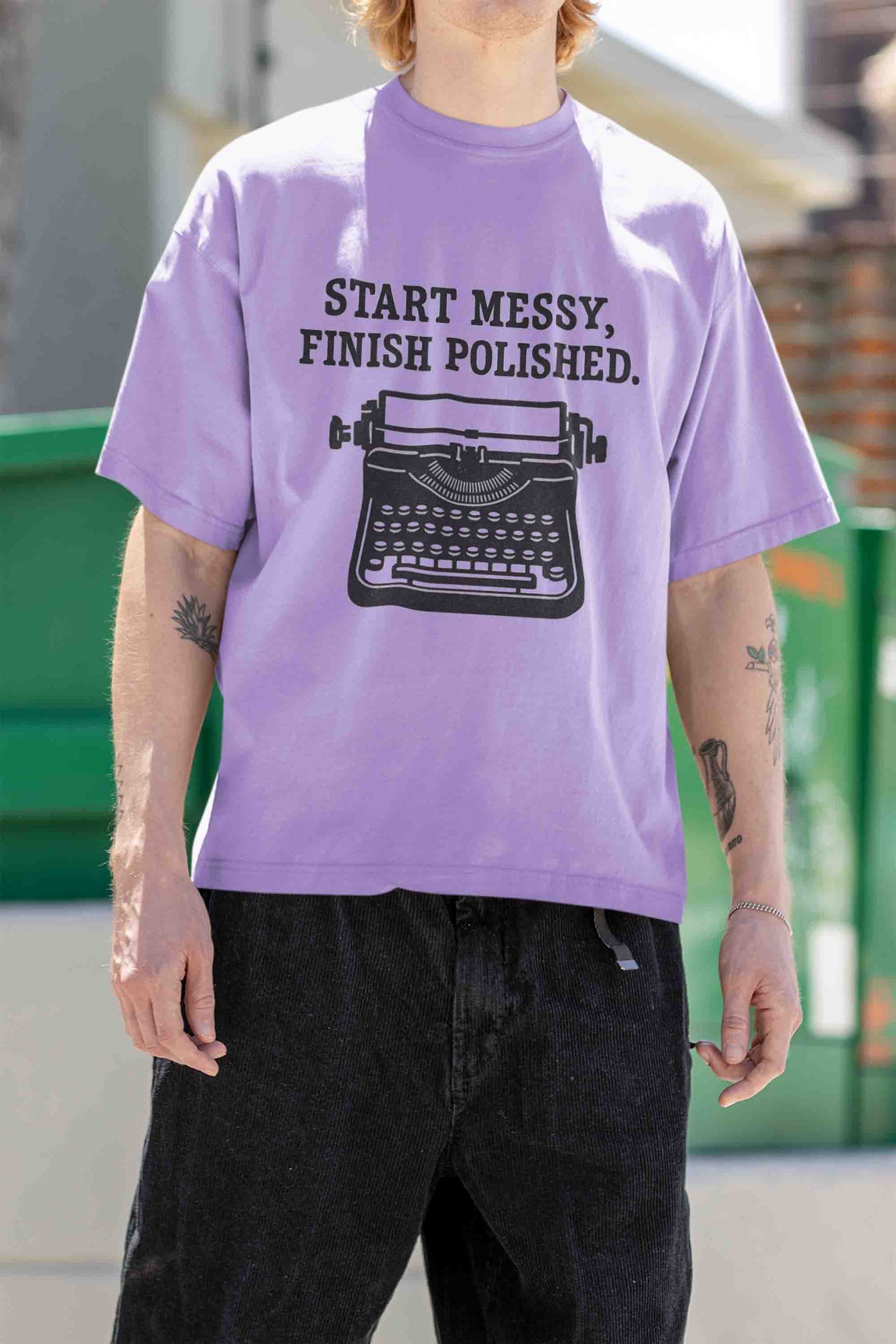 Man wearing oversized tee with arm‑tattoo, hip‑hop vibe
