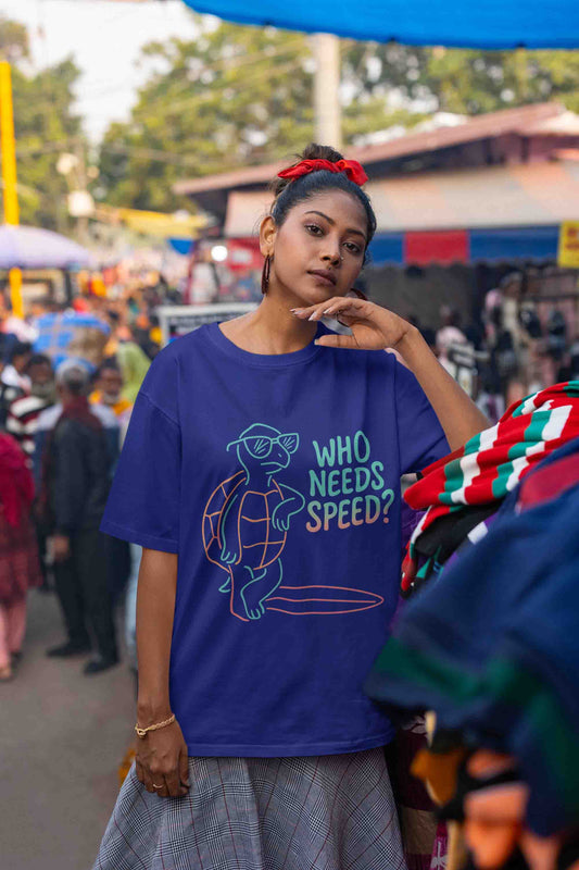 Oversized royal blue tee with neon pastel turtle and text: "Who Needs Speed?"